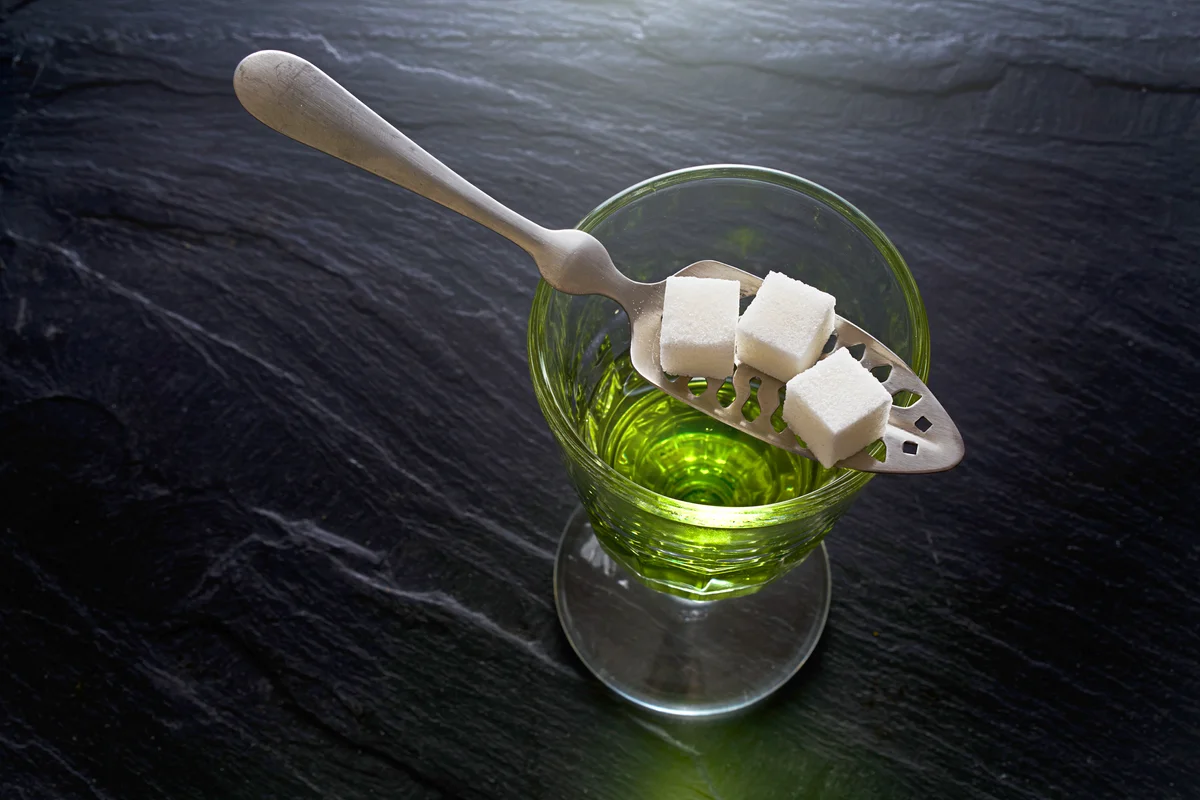 Absinthe in glass and spoon with sugar cubes