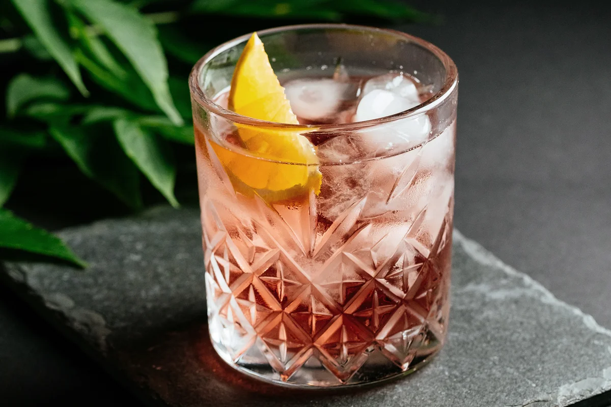 Glass of alcoholic cocktail with grenadine and absinthe and ice
