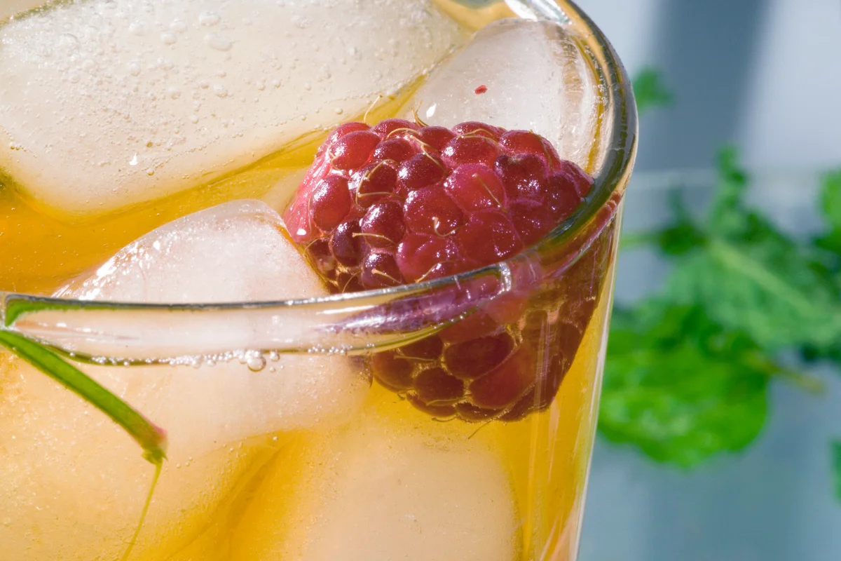 Glass of orange cocktail with raspberry