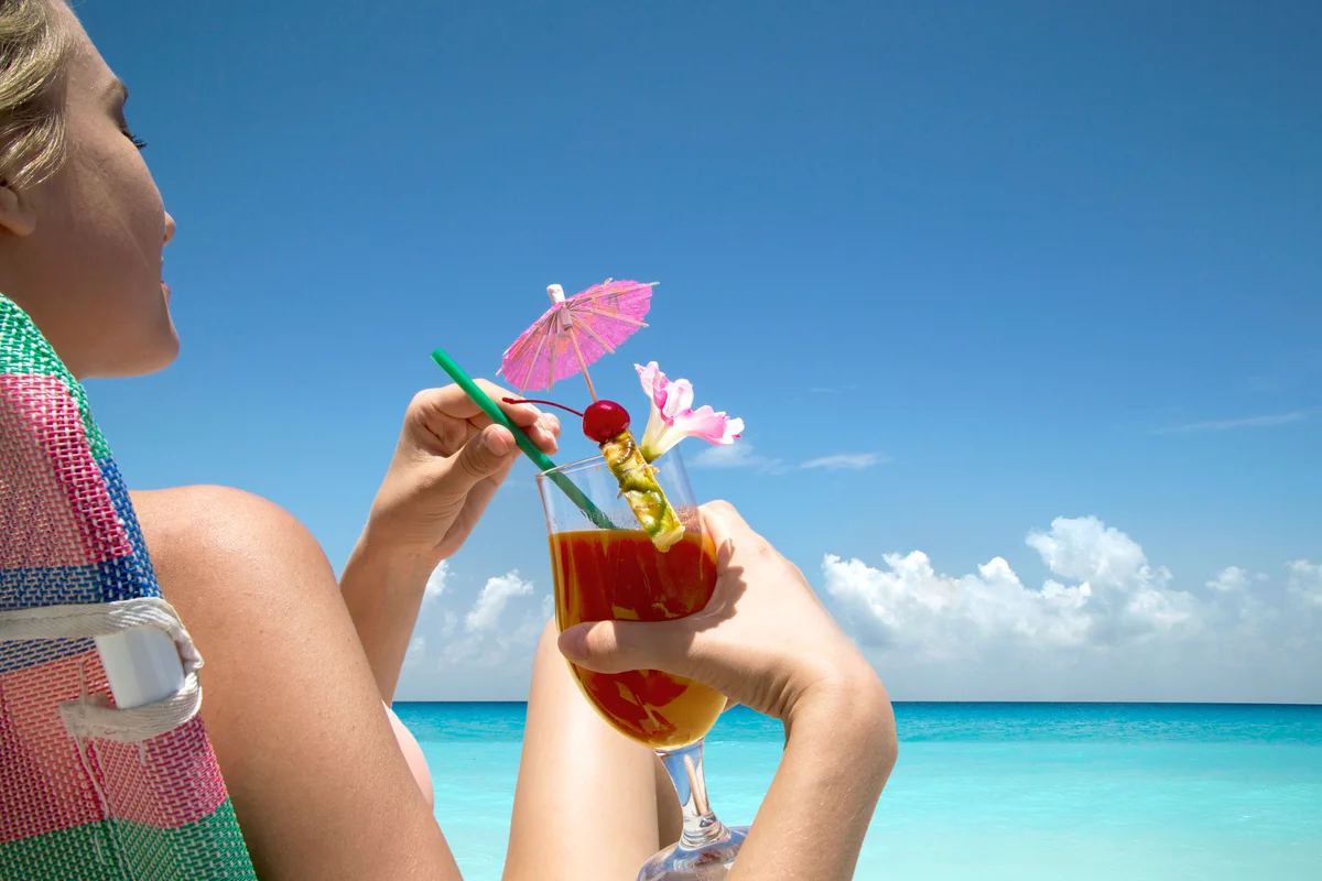 Woman with tropical drink on beach