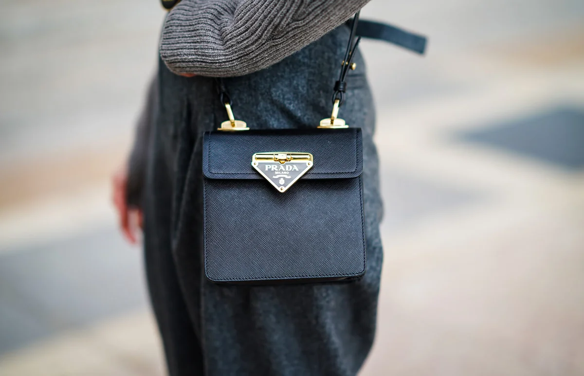 Natalia Verza wears a gray wool turtleneck pullover with a white shirt part and long sleeves from Nehera, gray large wool pants from Nehera, a Prada black leather bag | Getty Editorial Use