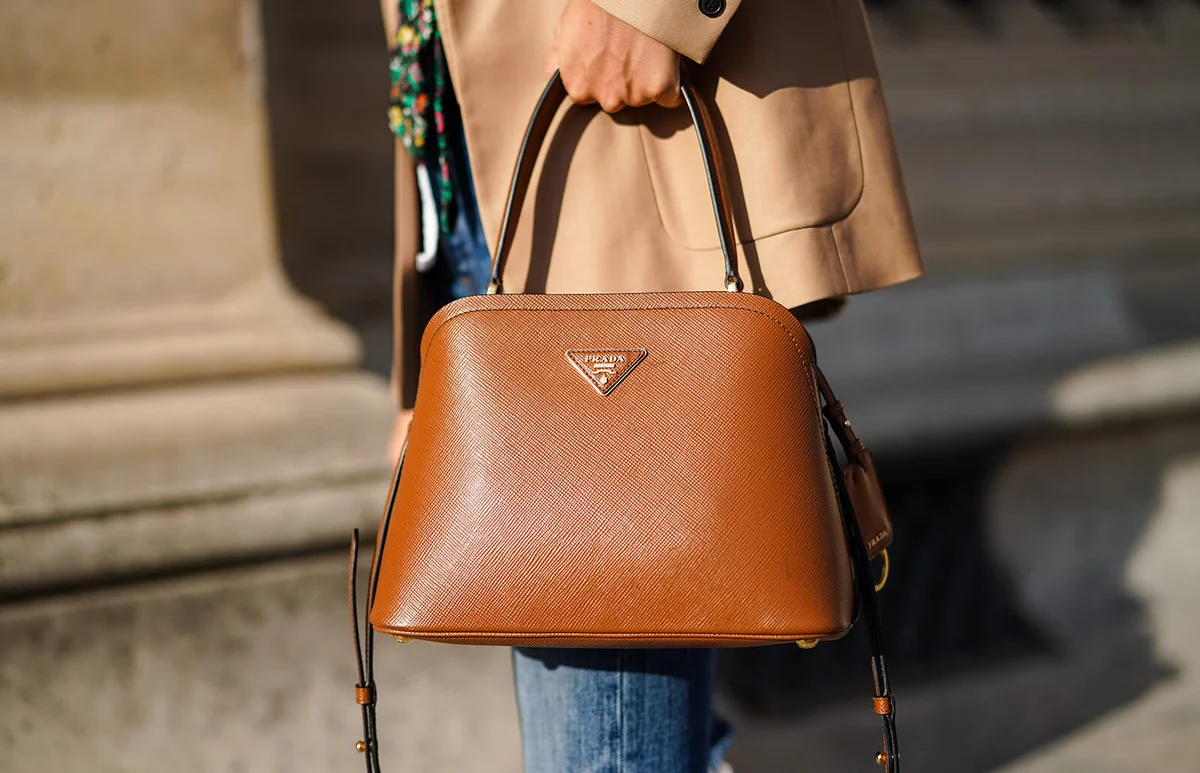 Natalia Verza wears a brown leather Prada bag, a beige jacket, blue ripped short jeans, on August 03, 2020 in Paris, France