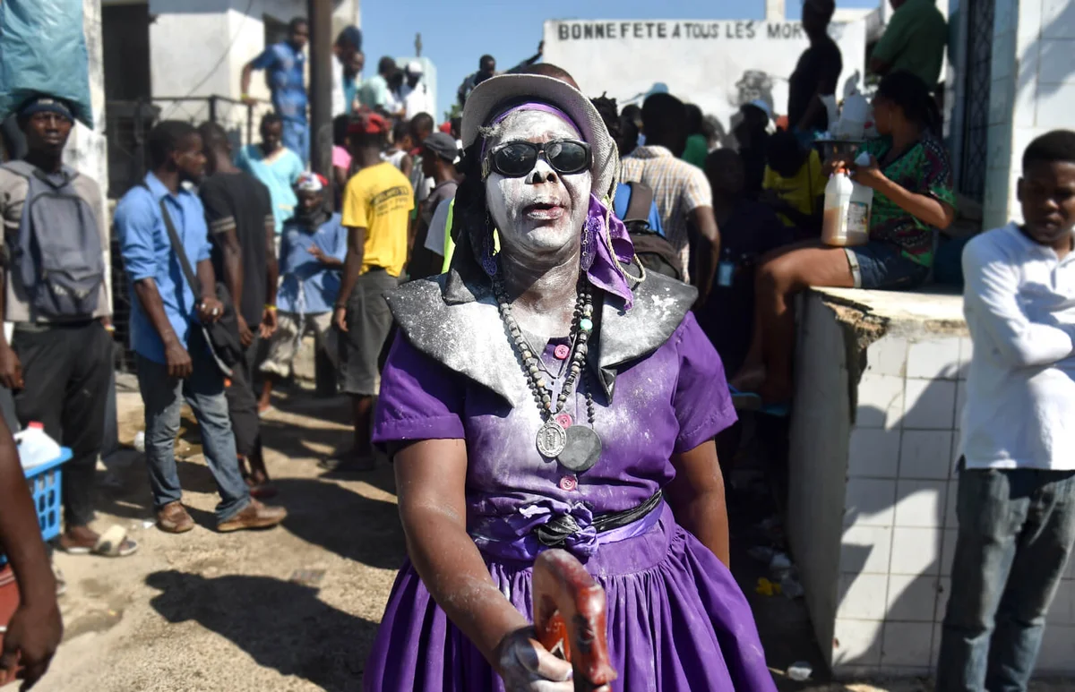 A woman devotee in the role of a spirit known as a Gede is seen during ceremonies honoring the Haitian voodoo spirit of Baron Samdi on the Day of the Dead at the National Cemetery in Port-au-Prince on November 1, 2018 | Getty Editorial Use