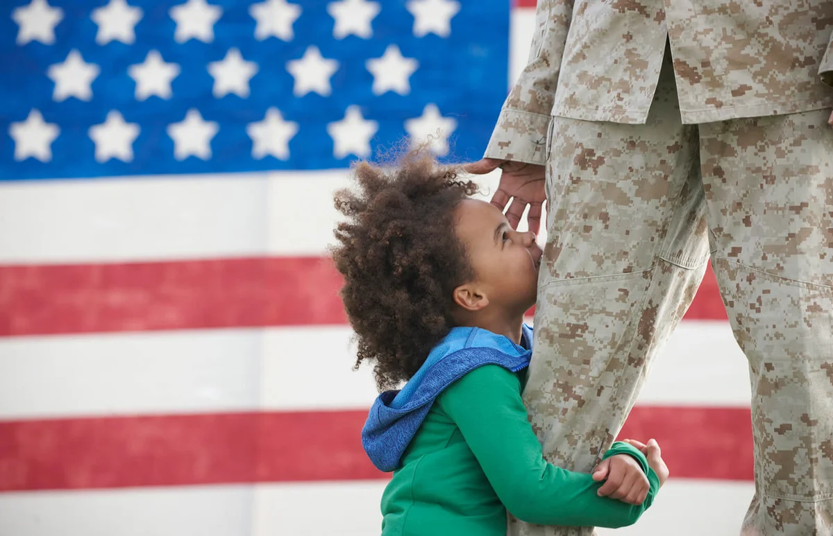 girl hugging leg of returning soldier