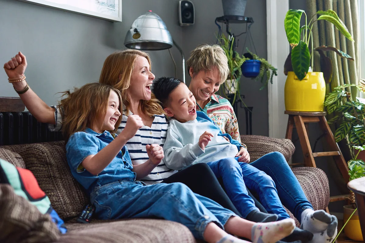 Cheerful family with two mums watching tv at home