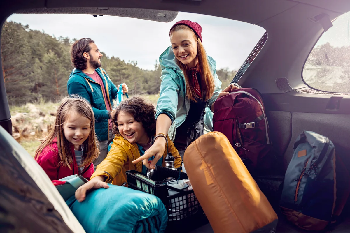 Young family getting the camping supplies out of the car
