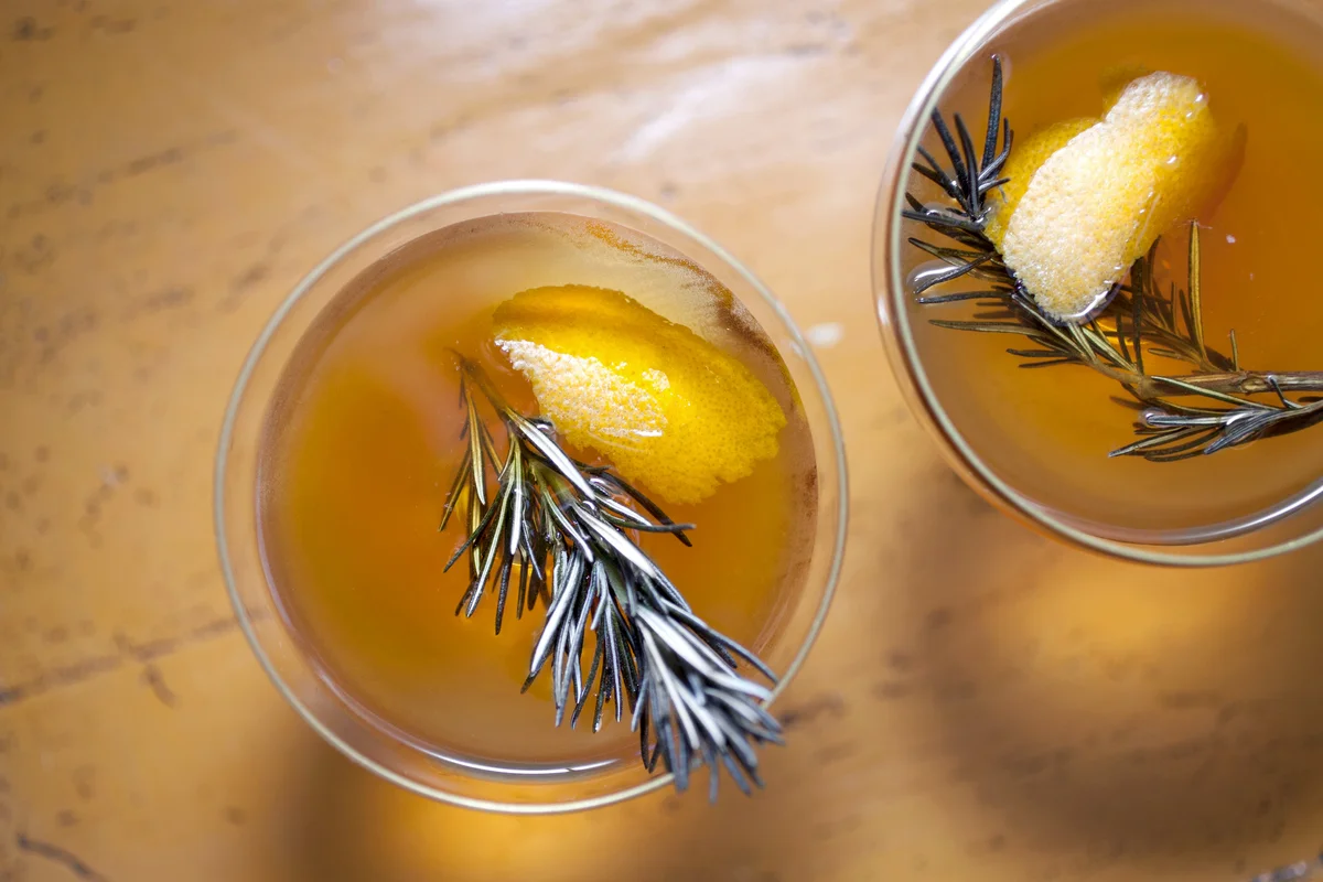 Artisan cocktails garnished with rosemary and orange zest