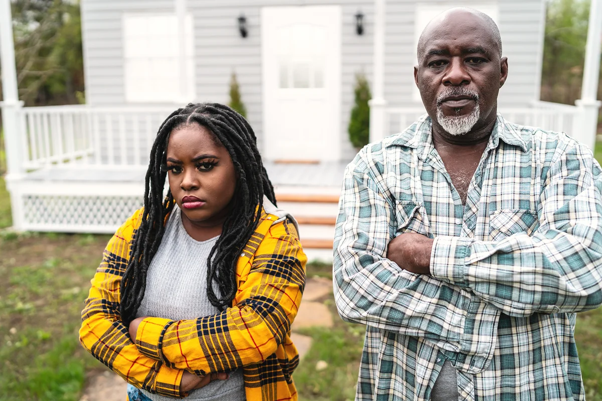 Father and daugther standing arms crossed outdoors