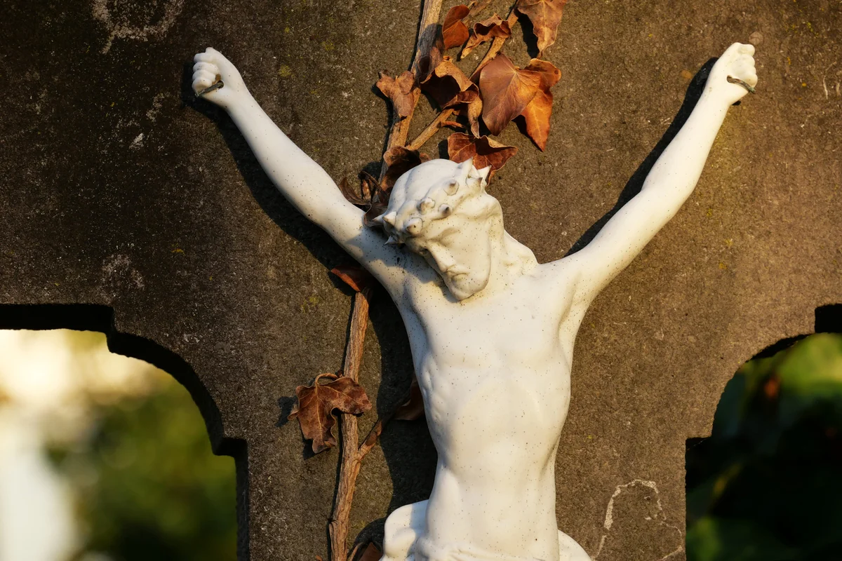 Abandoned white crucifix on a gray stone under sunlight