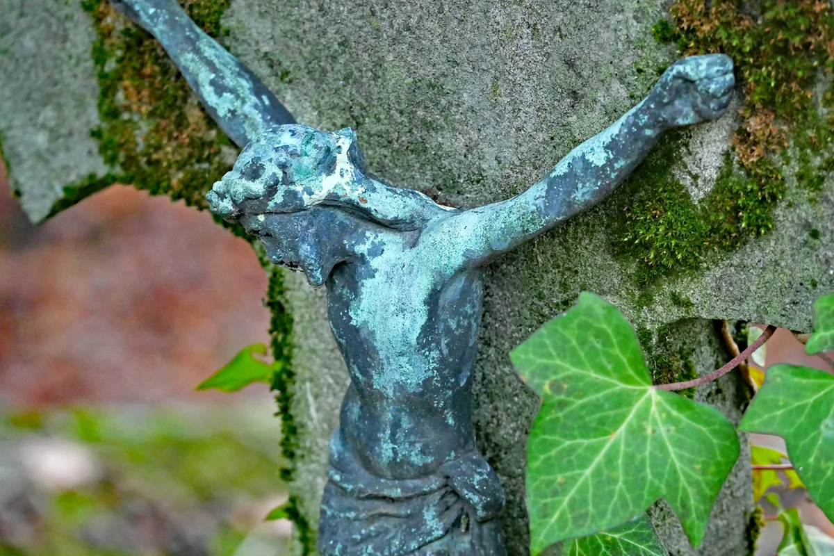 Old crucifix on a weathered stone cross with ivy