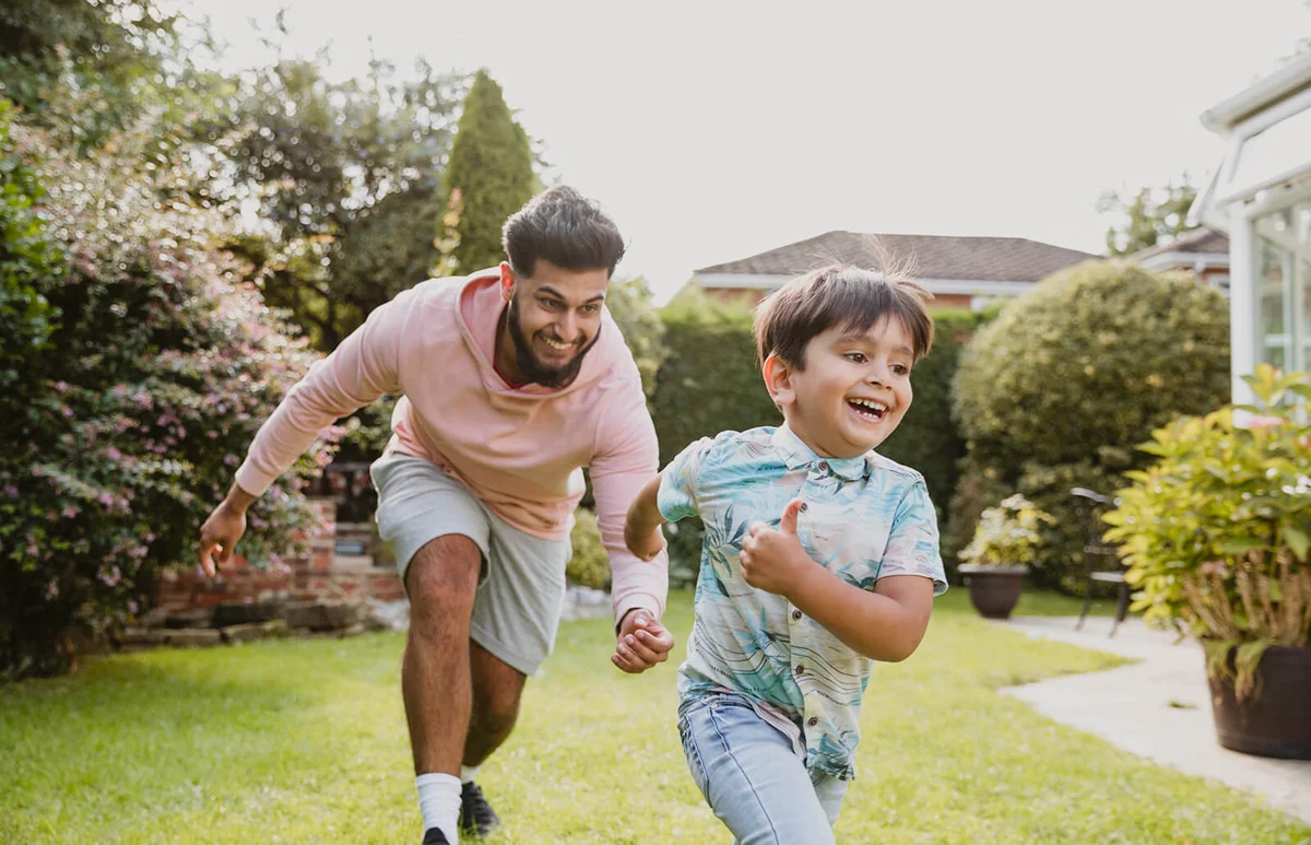 Uncle chasing the children in the garden during outdoors playtime