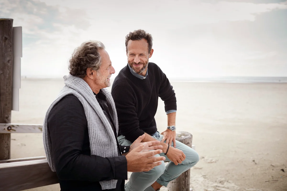 Two men talking on boardwalk on the beach