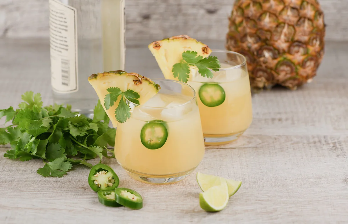 Two glasses with cocktail with pineapple, jalapeno and coriander