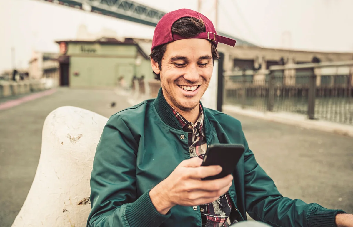 smiling young man using cell phone
