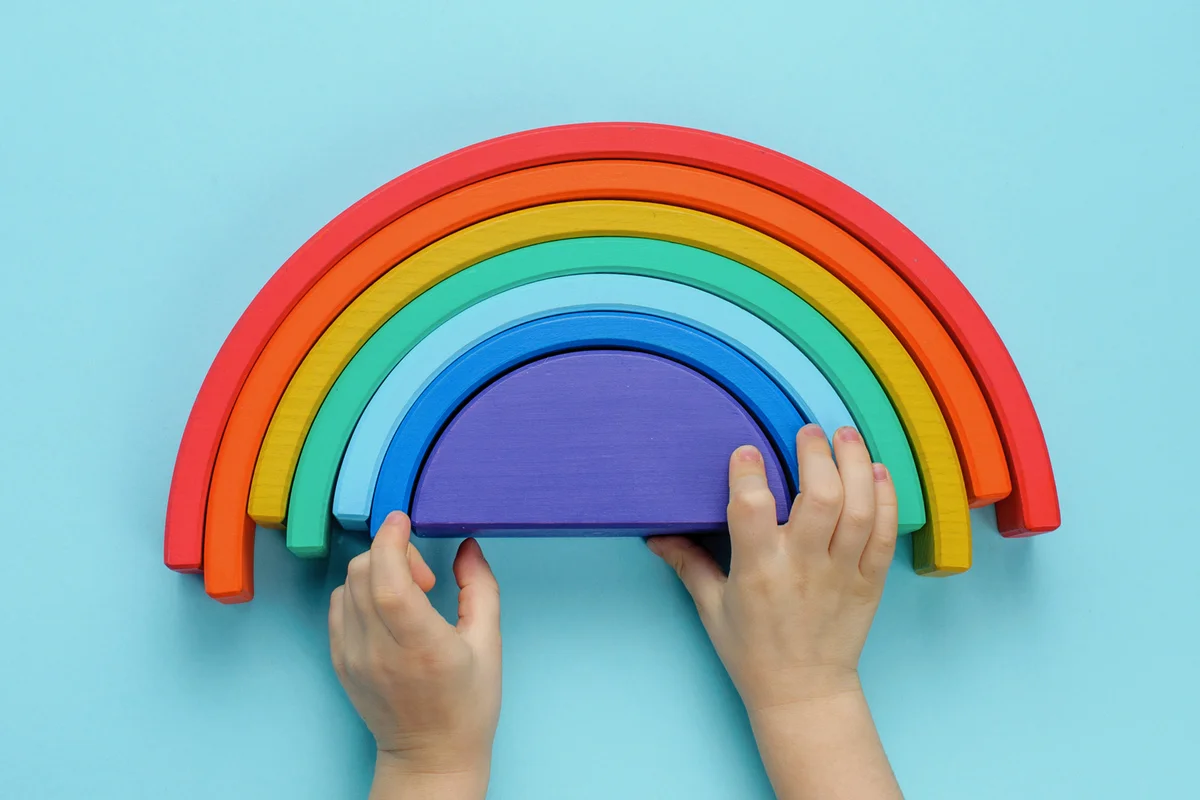 Kids hands playing with wooden toy rainbow