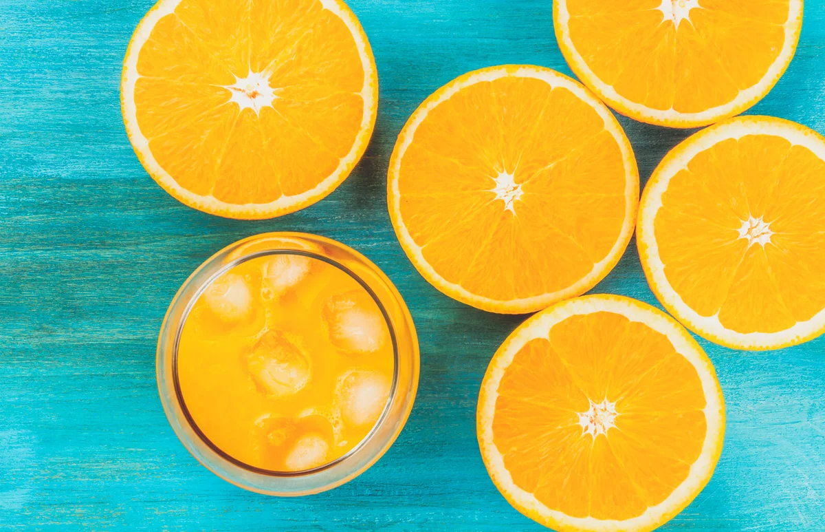 glass of fresh orange juice with orange halves