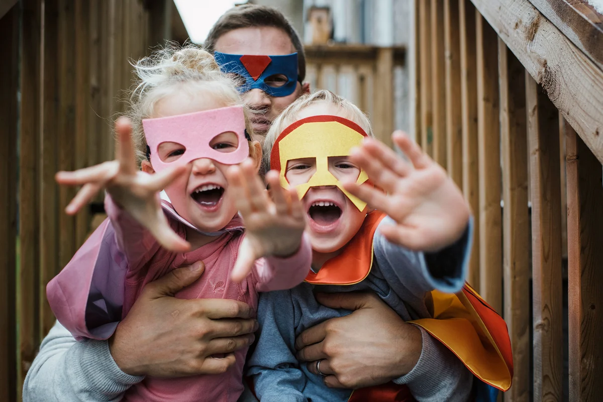 Portrait of children with father in superhero costumes