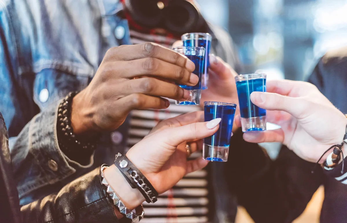 Friends drinking shots, close up of hands