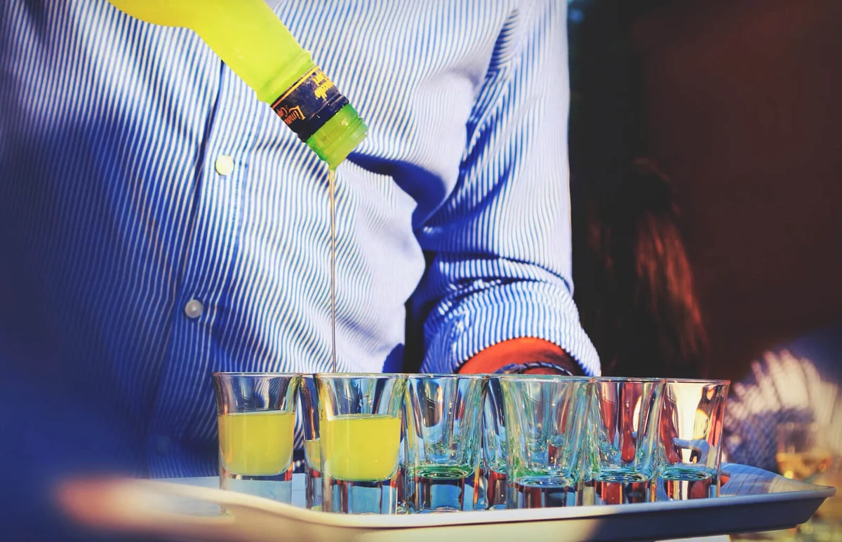 Man Pouring Alcohol In Shot Glass At Bar