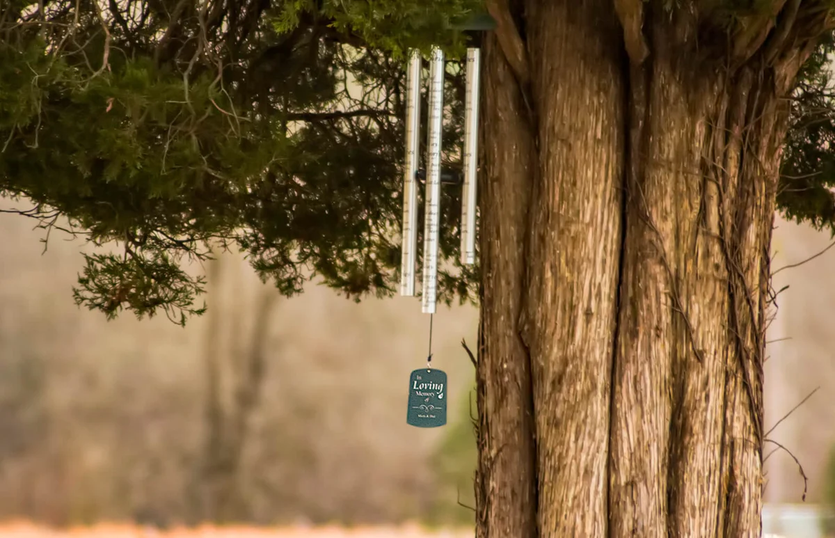 Memorial Sonnet Chime dangling from a branch on a pine tree