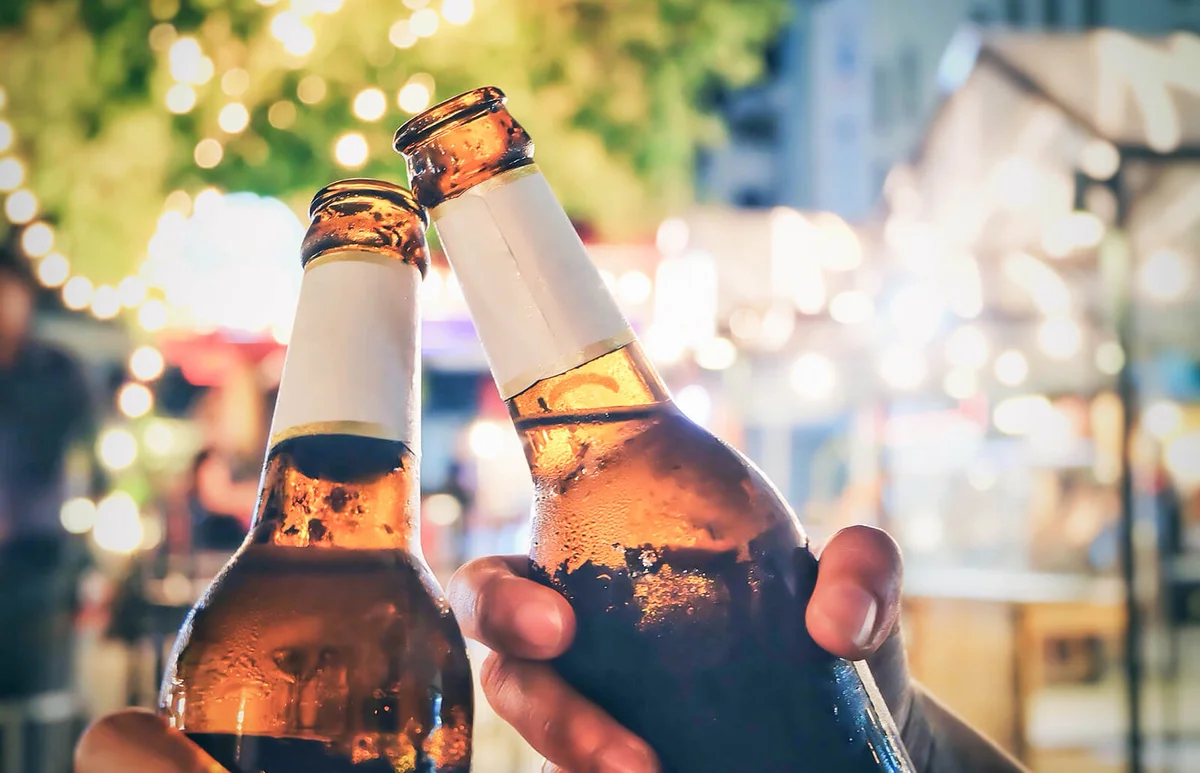 Friends Toasting Beer Bottles At Night