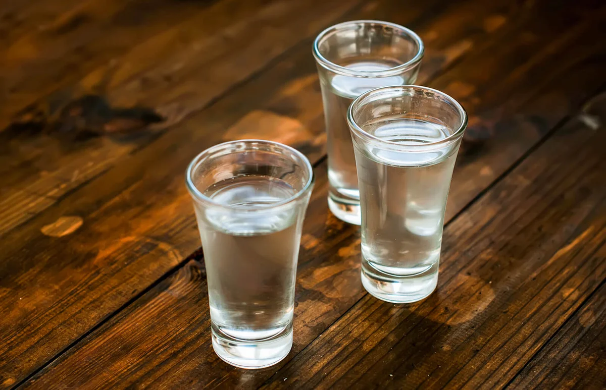 Cold vodka in a glass on a wooden table