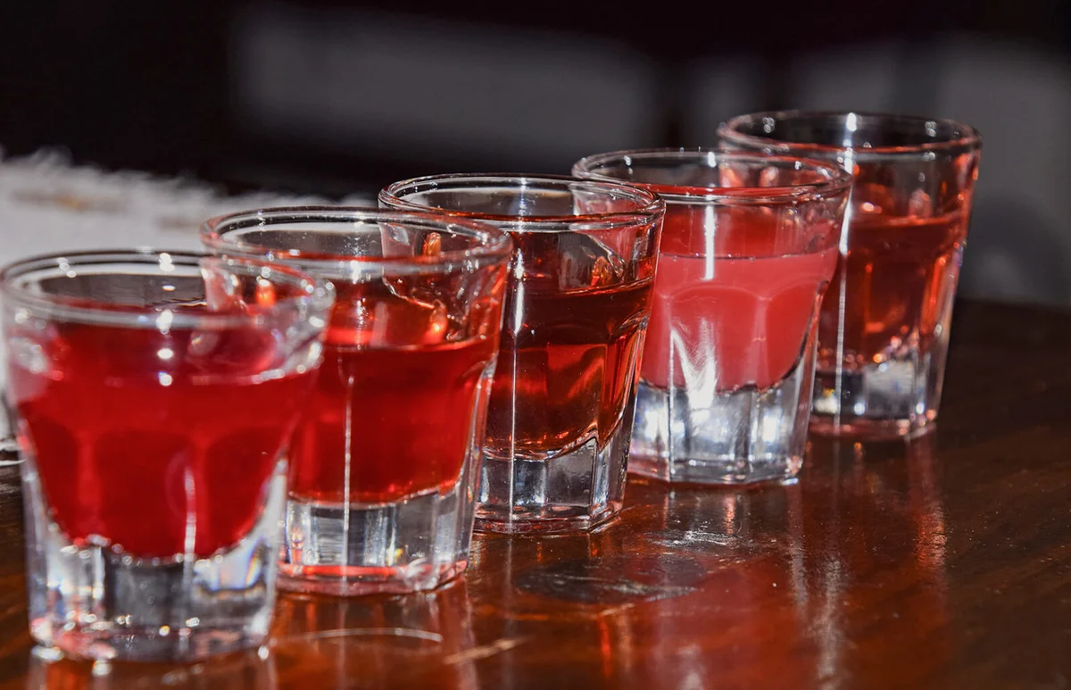 Alcohol In Shot Glasses Arranged On Wooden Table