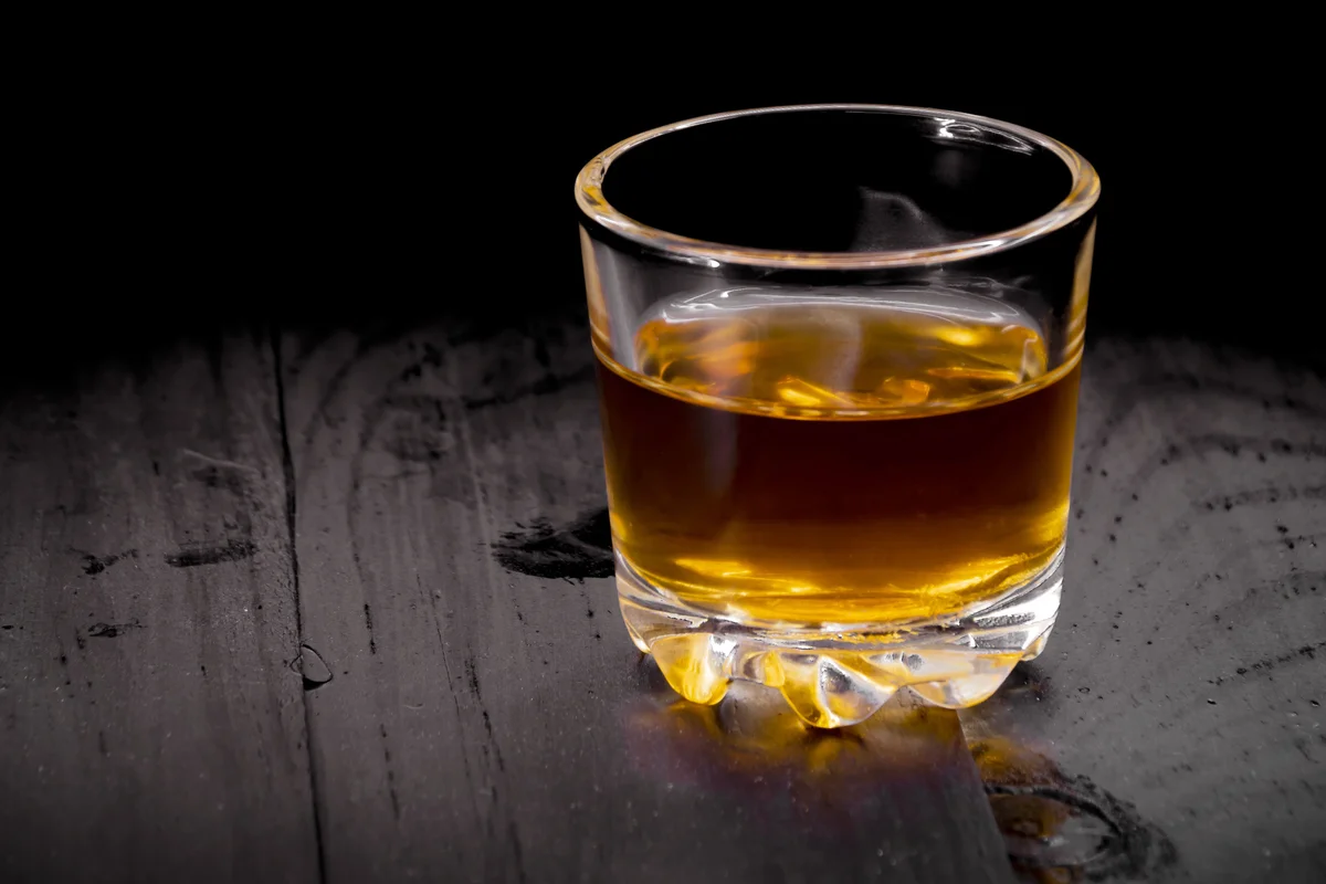 Whiskey glass of cognac on a black tree
