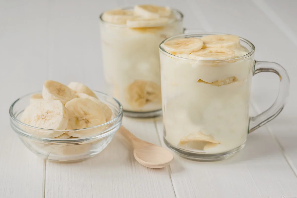Freshly made banana pudding in the circles and the slices of banana on a white table