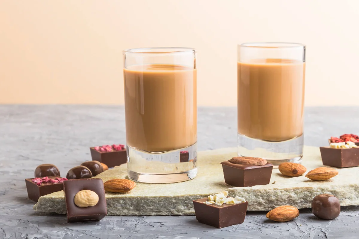 Sweet chocolate liqueur in glass with chocolate candies