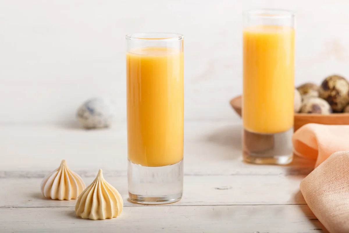 Sweet egg liqueur in glass with quail eggs and meringues