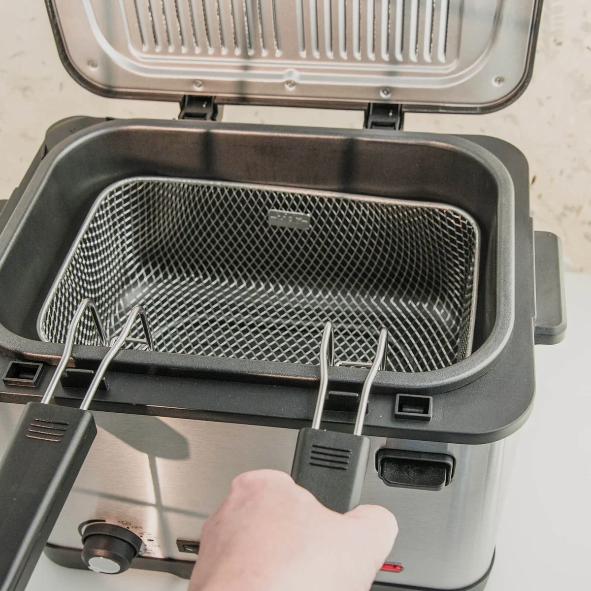 Mesh cooking basket in tank of deep fryer