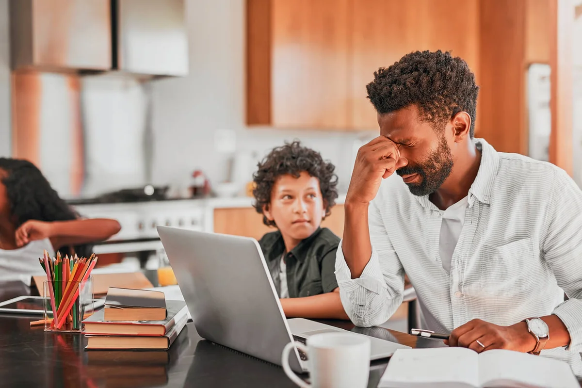 man using his laptop while sitting with his son