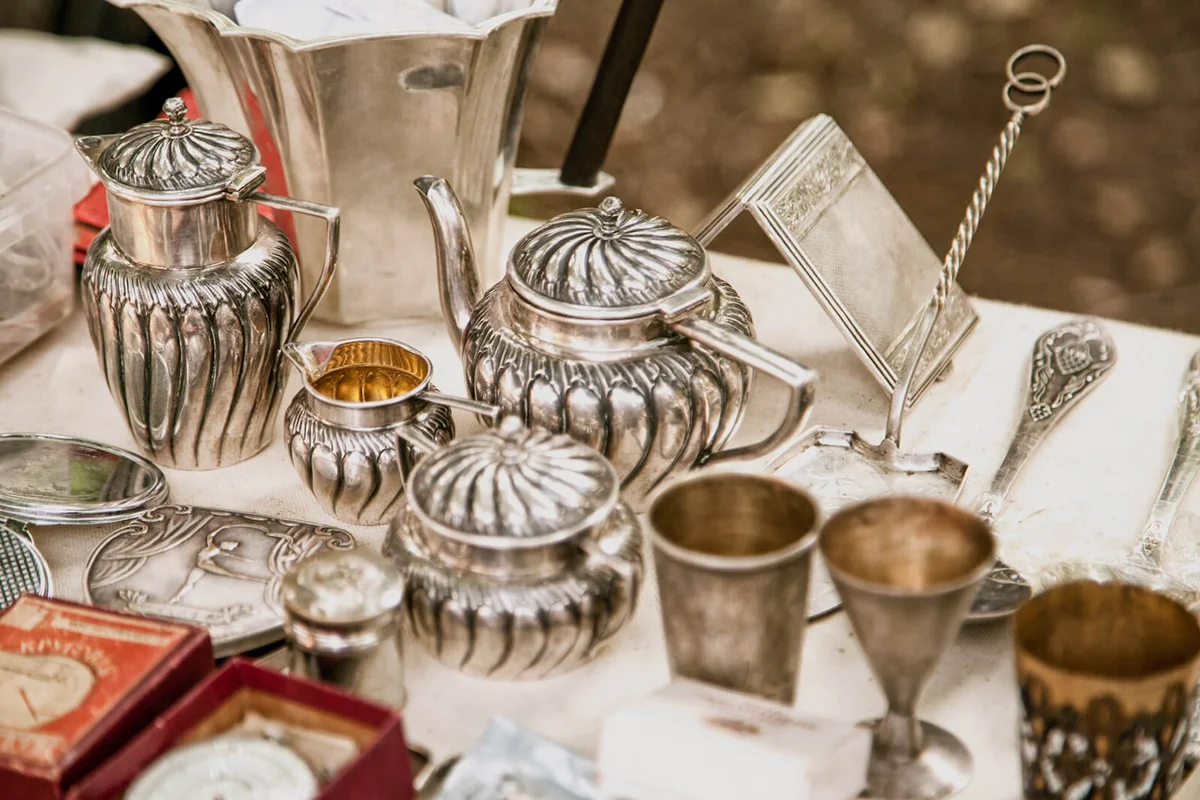 Antique silver teapots, creamer and other utensils at a flea market