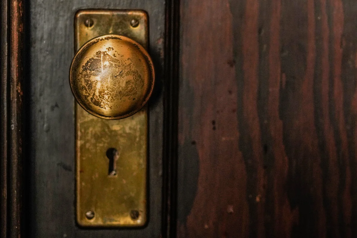 Weathered and old brass door knob on wooden door