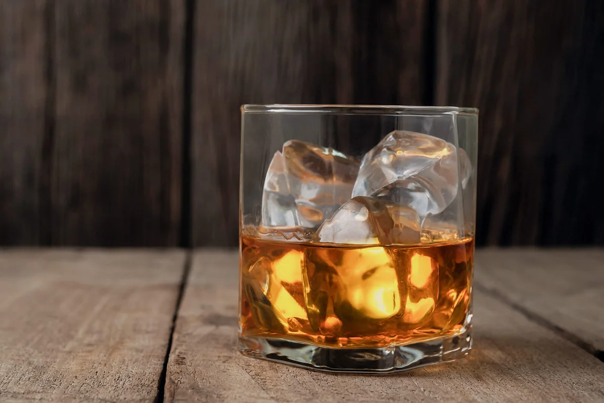 whiskey bottle on wooden table against wooden wal