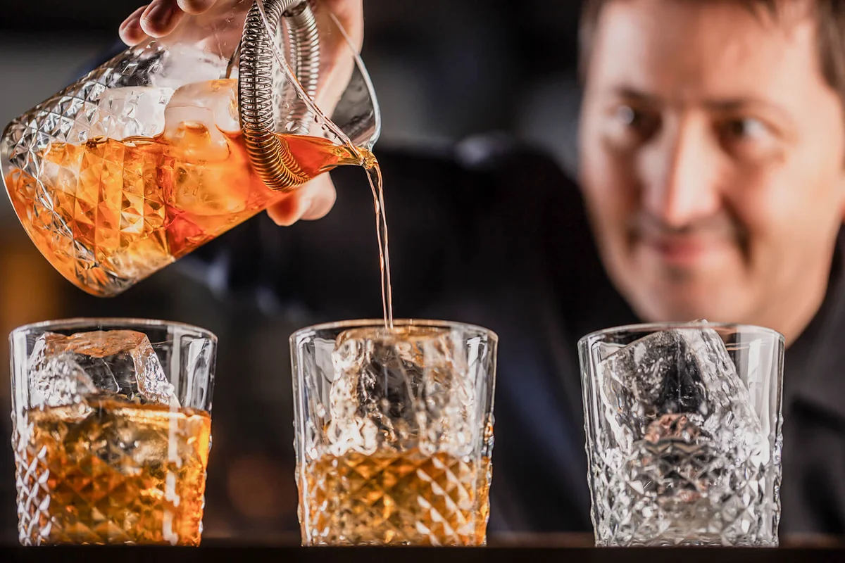 Whisky bourbon on ice being prepared by a professional bartender