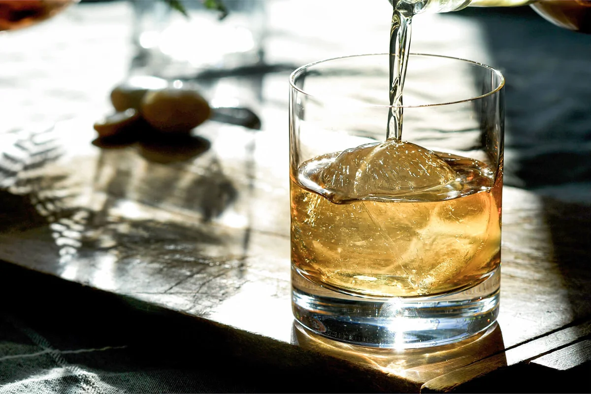 Classic Prohibition Manhattan Cocktail in Old Fashioned Rocks Glass being poured