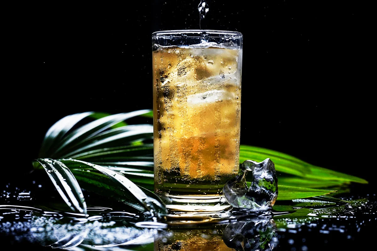 selective focus drink alcohol and water glass with dark rum