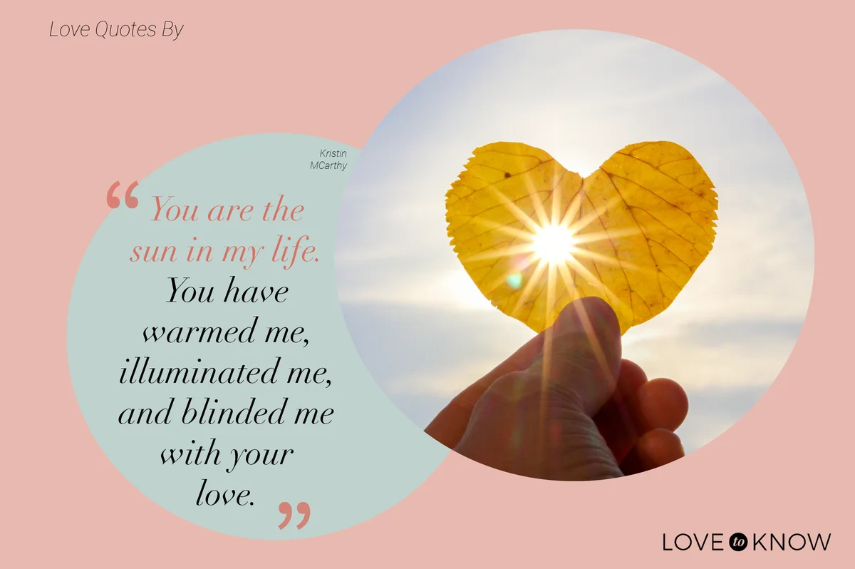 Hand holding yellow leaf of heart shape with sun rays shining through