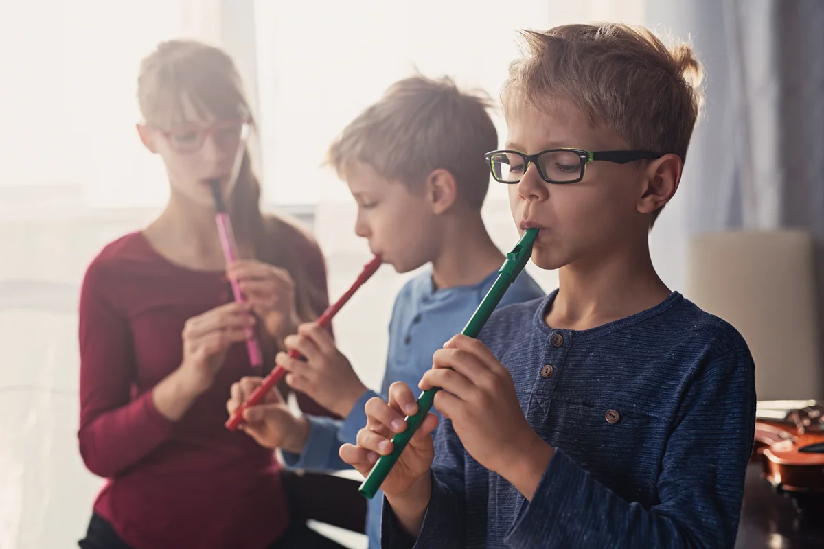 Three kids playing flutes together -