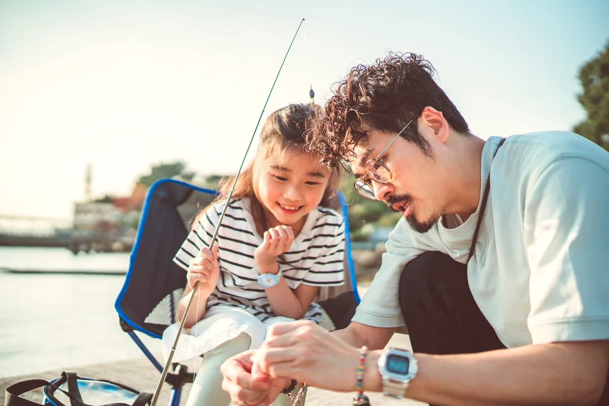 Young dad teaching her daughter fishing at pier joyfully