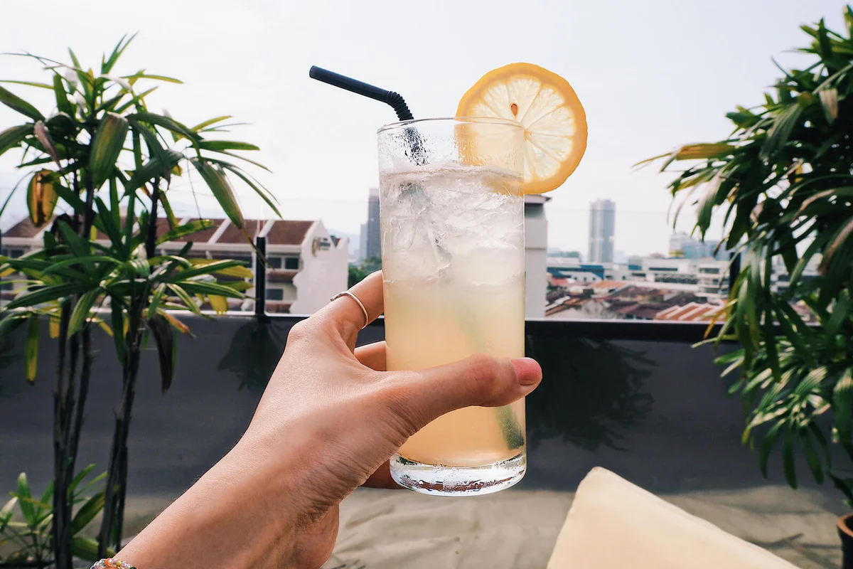 Cropped Hand Of Woman Holding Drink Against Sky