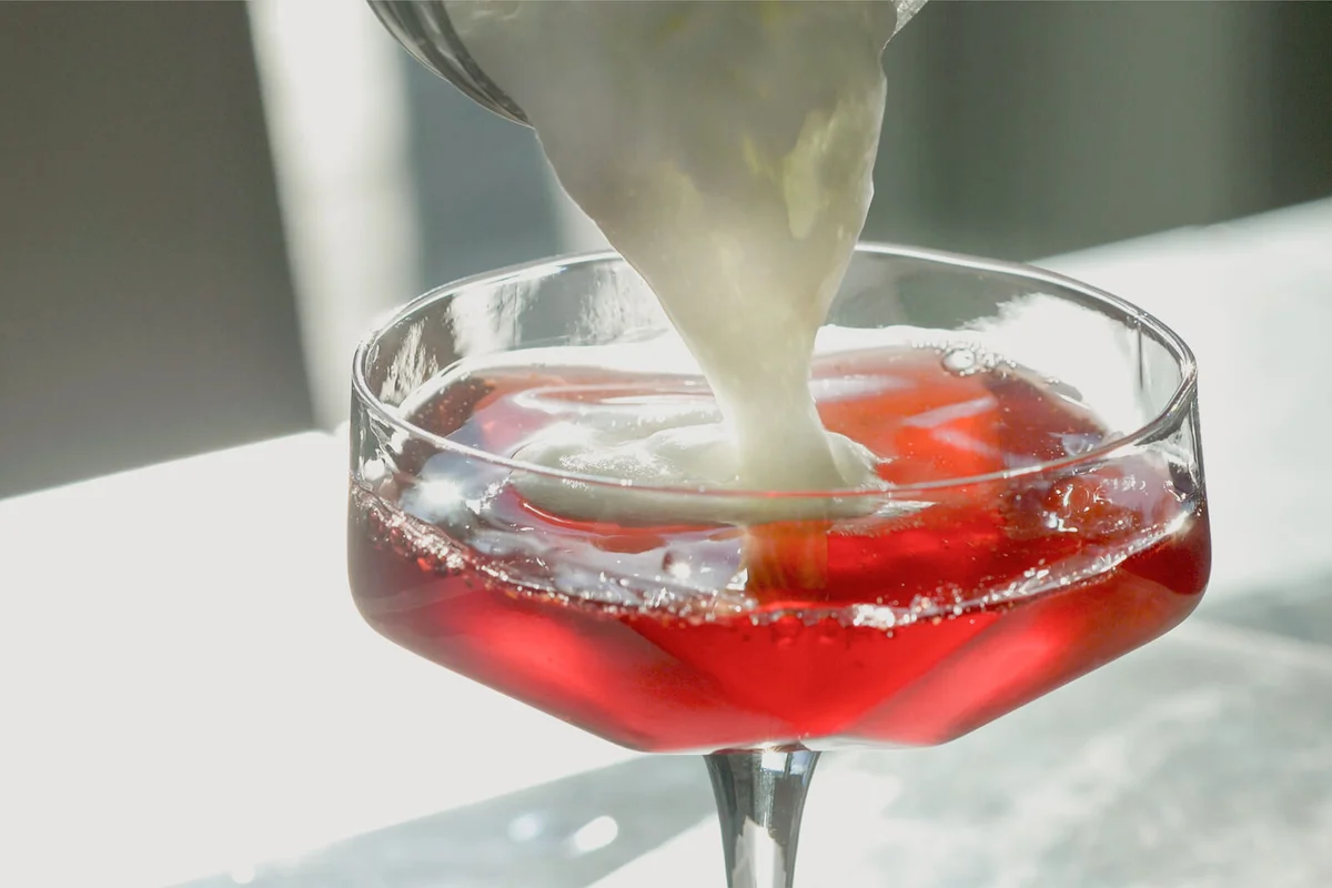 Classic Prohibition Cocktail with egg whites and garnished with lime slice and thyme