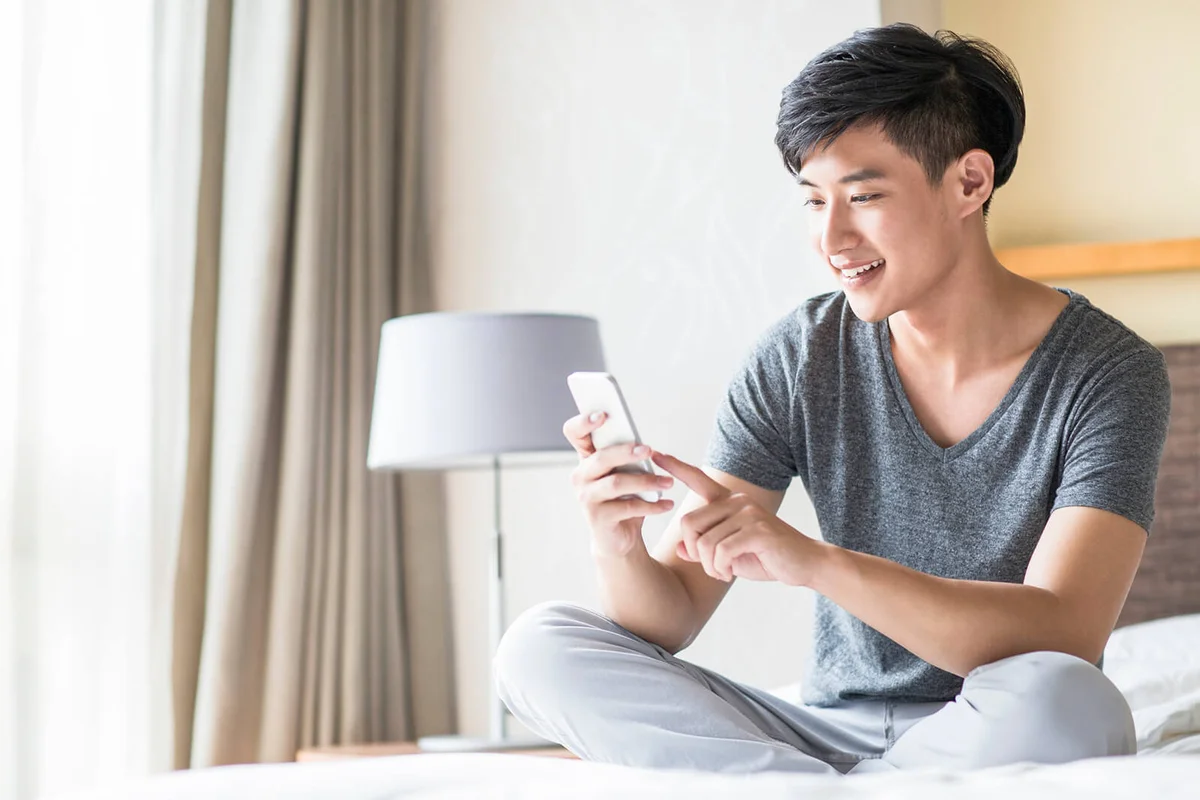 Young man using smart phone on bed