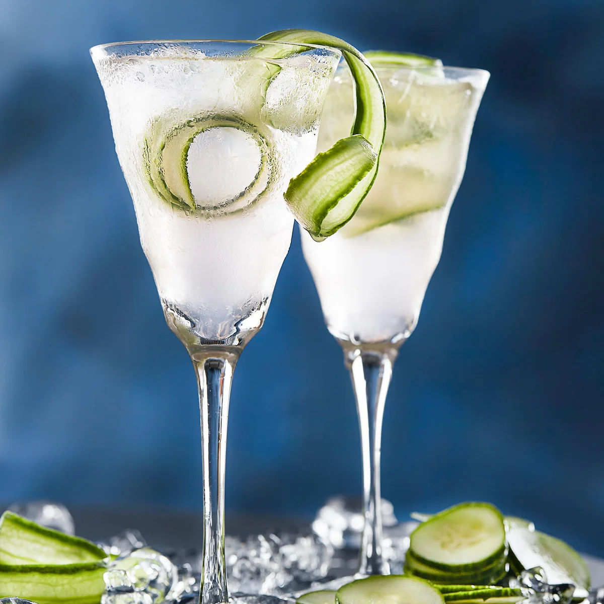 two iced pink cocktails with cucumber garnish