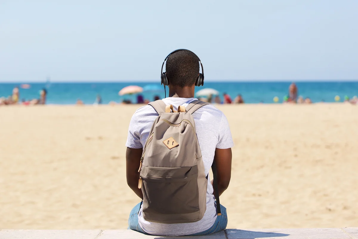 Man sitting by the beach with backpack