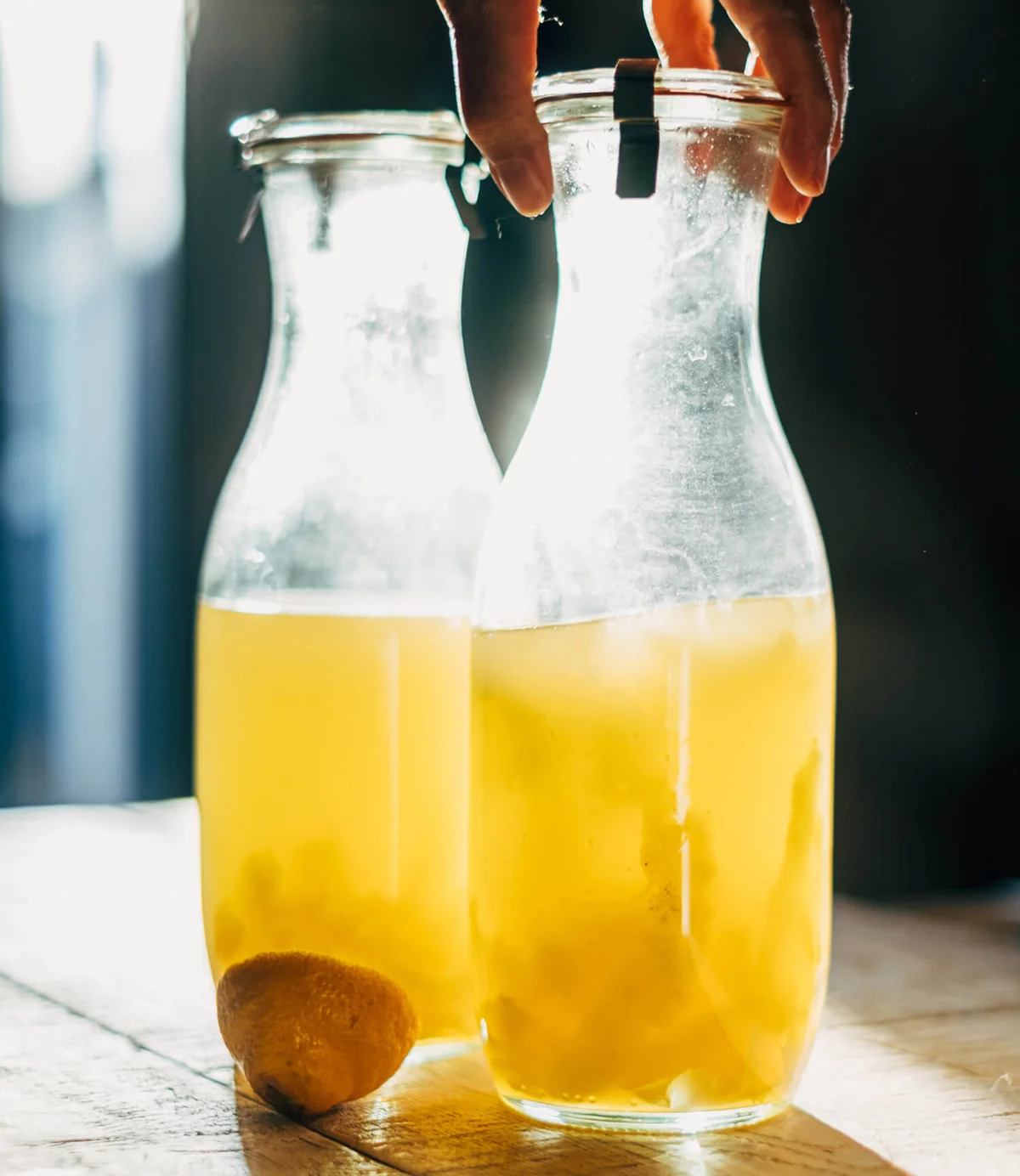 Human Hand Holding Bottle With Limoncello Drink On Table
