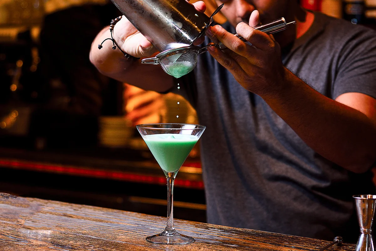 bartender filtering the mix from de shaker