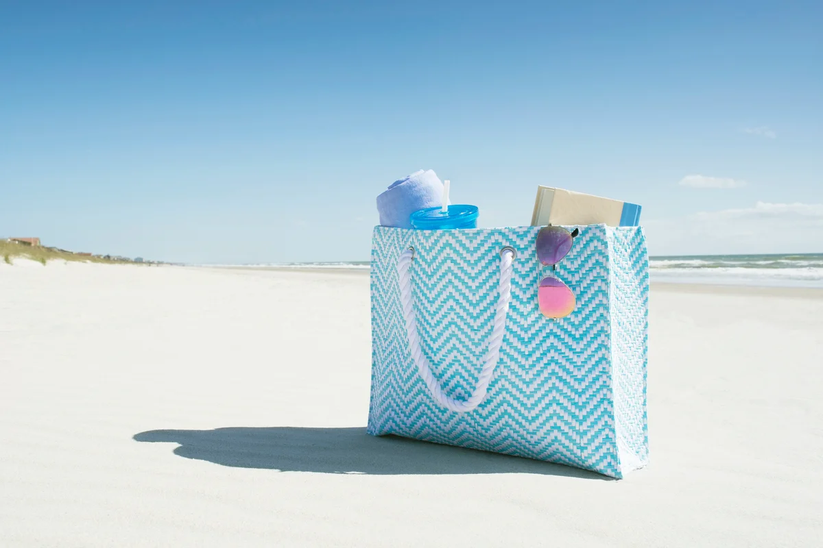 Bag with towel, book and sunglasses on empty beach